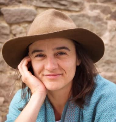 Veneta Dimitrova mit Hut vor einer Steinwand.