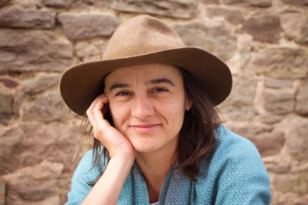 Veneta Dimitrova mit Hut vor einer Steinwand.